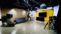 Sydney TV Studio Hire with modern television studio with a presentation desk, large screen, and comfortable seating area.